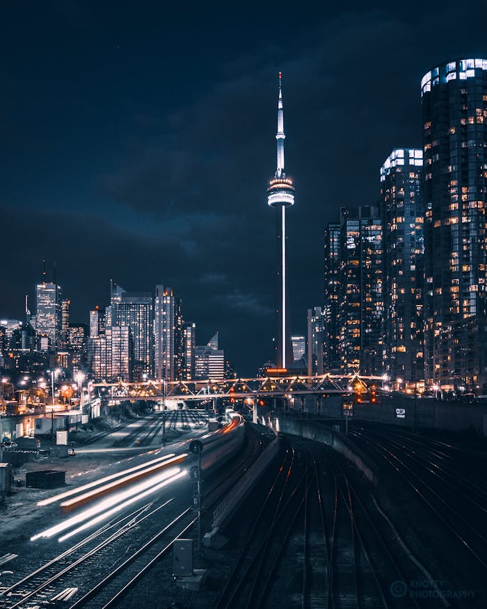 Stunning night view of Toronto skyline featuring the CN Tower and blurred train motion.